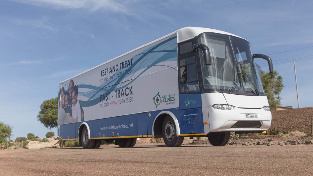 mobile health clinic on dirt road under blue sky